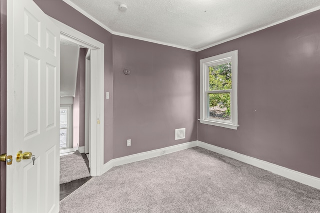 spare room with carpet, baseboards, visible vents, and a textured ceiling