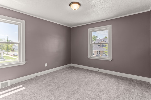 carpeted spare room with visible vents, crown molding, a textured ceiling, and baseboards