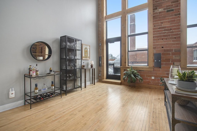 sitting room with light wood-type flooring, baseboards, and a high ceiling