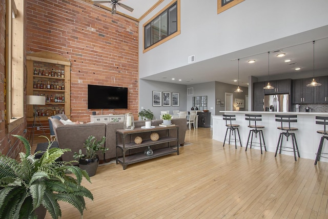 living room featuring light wood-type flooring, visible vents, and a ceiling fan