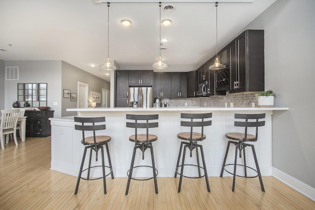 kitchen with a peninsula, appliances with stainless steel finishes, a breakfast bar area, and light countertops