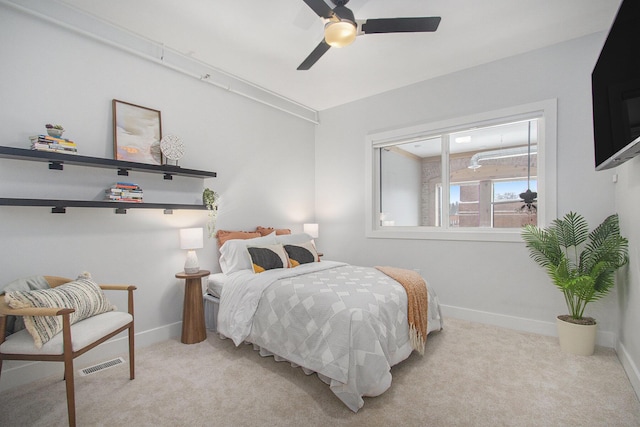 bedroom with light colored carpet, ceiling fan, visible vents, and baseboards