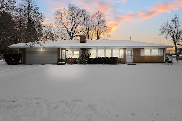 single story home featuring brick siding, a chimney, and an attached garage