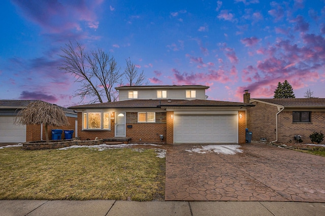 view of front of house with an attached garage, decorative driveway, a lawn, and brick siding