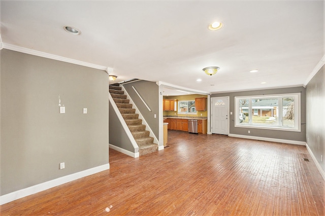 unfurnished living room with crown molding, recessed lighting, wood finished floors, baseboards, and stairs