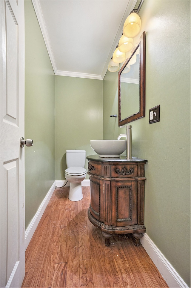 bathroom featuring baseboards, crown molding, toilet, and wood finished floors