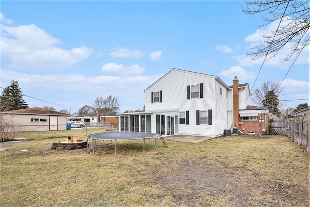 back of house featuring a fenced backyard, central AC, a sunroom, a lawn, and a chimney