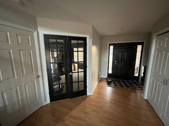 foyer entrance with baseboards, wood finished floors, and french doors