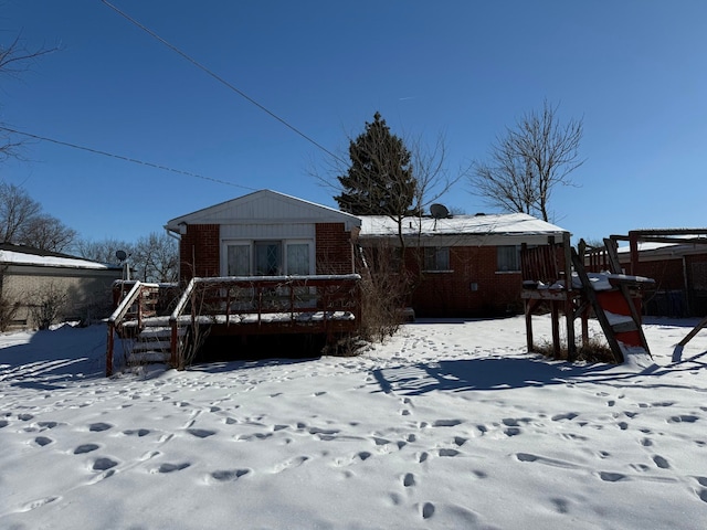 snow covered rear of property featuring brick siding