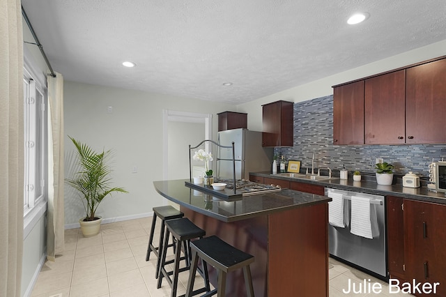 kitchen with freestanding refrigerator, a kitchen island, dark countertops, and stainless steel dishwasher