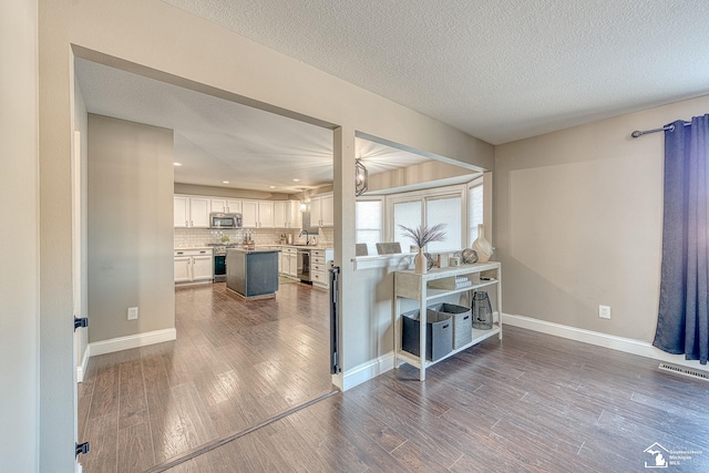 interior space with a textured ceiling, wood finished floors, visible vents, and baseboards