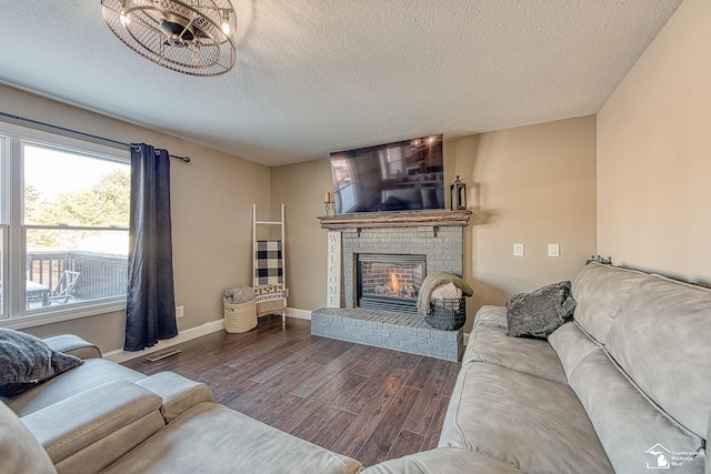 living room featuring dark wood-style floors, a fireplace, visible vents, a textured ceiling, and baseboards