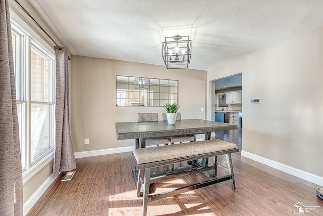 dining area with baseboards, a textured ceiling, a chandelier, and wood finished floors