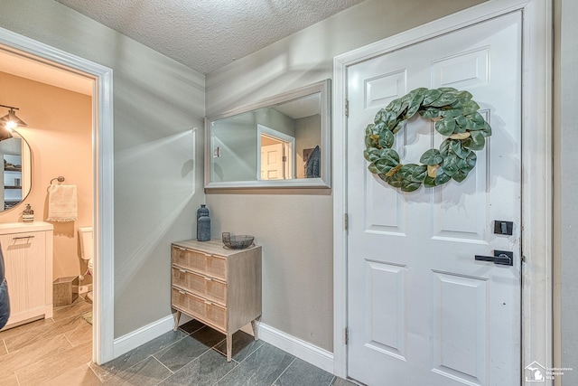 foyer with a textured ceiling and baseboards