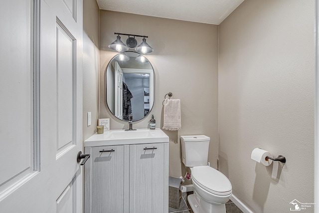 bathroom with baseboards, vanity, and toilet