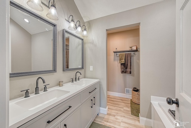 bathroom featuring double vanity, baseboards, a sink, and wood finished floors