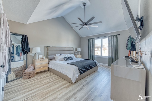 bedroom featuring light wood-type flooring, ceiling fan, a textured ceiling, and lofted ceiling