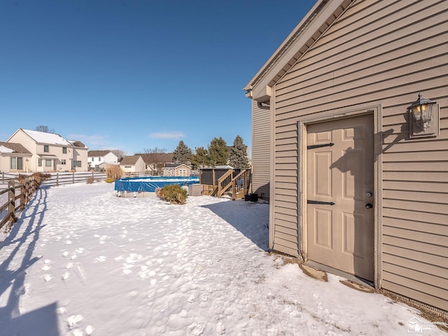 yard layered in snow with a residential view, fence, and an outdoor pool