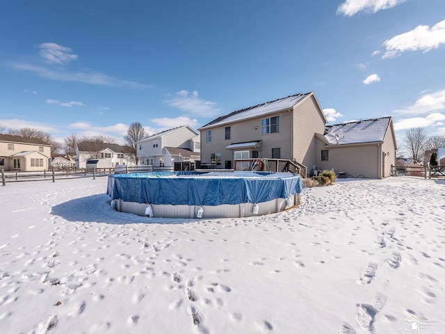 snow covered property featuring a residential view, a covered pool, and fence