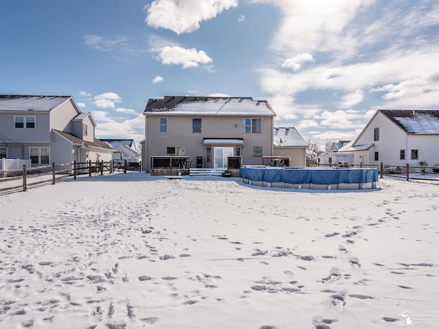 snow covered house with a residential view, fence, and a fenced in pool