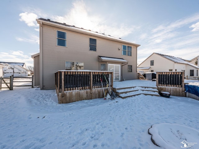 snow covered rear of property with fence