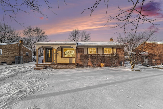 view of front of property with covered porch, brick siding, and a chimney