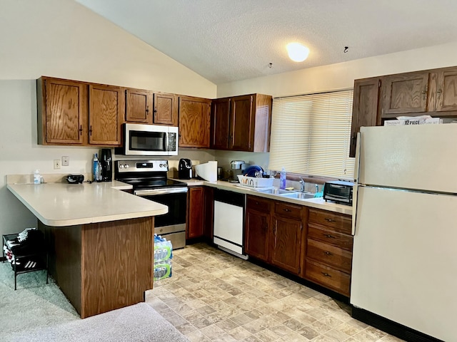 kitchen with lofted ceiling, a textured ceiling, a peninsula, light countertops, and appliances with stainless steel finishes