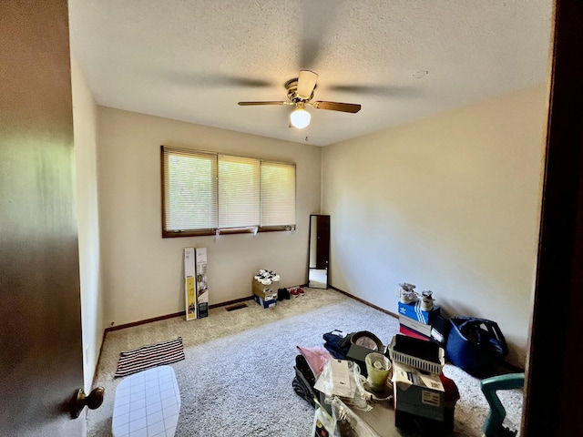 interior space with carpet, baseboards, a ceiling fan, and a textured ceiling