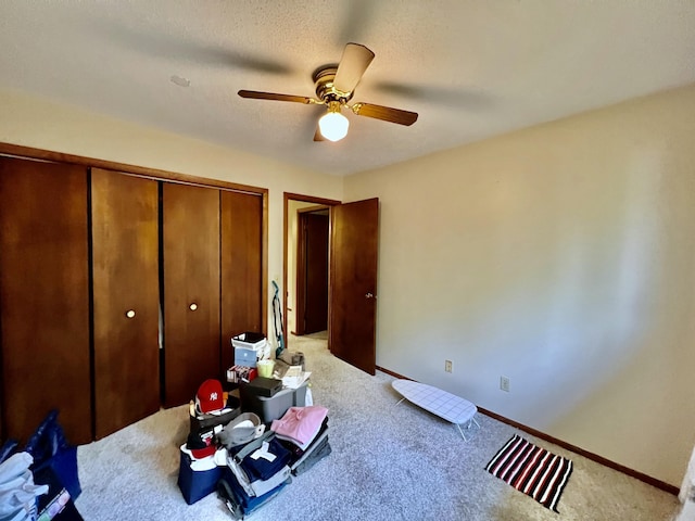 carpeted bedroom with a textured ceiling, ceiling fan, a closet, and baseboards