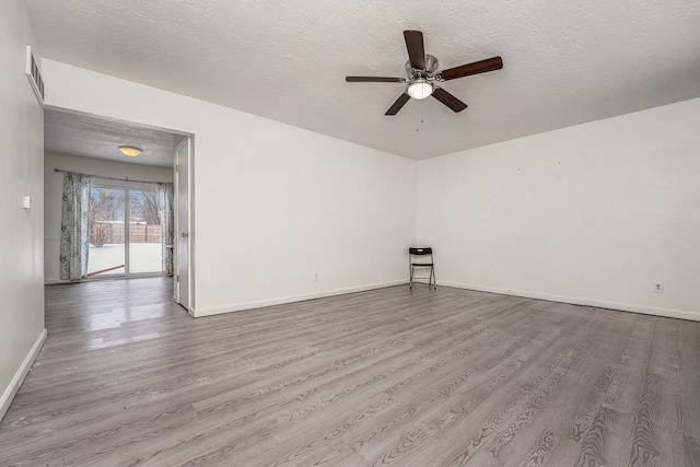 spare room with light wood finished floors, ceiling fan, baseboards, and a textured ceiling