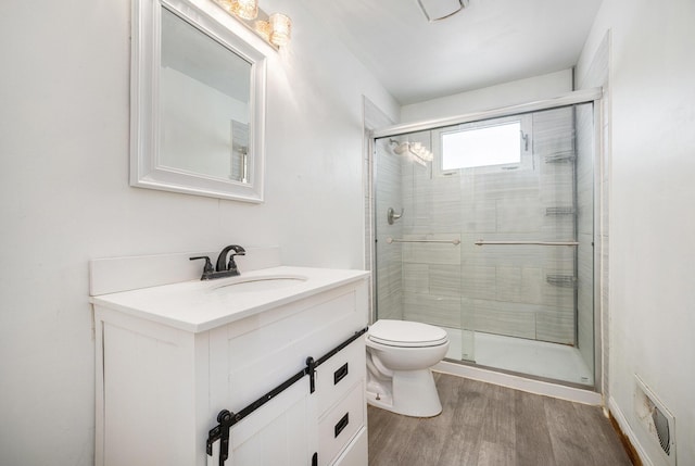 bathroom with toilet, wood finished floors, visible vents, vanity, and a shower stall