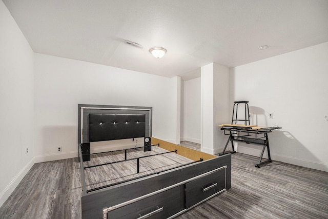 bedroom with visible vents, baseboards, and wood finished floors