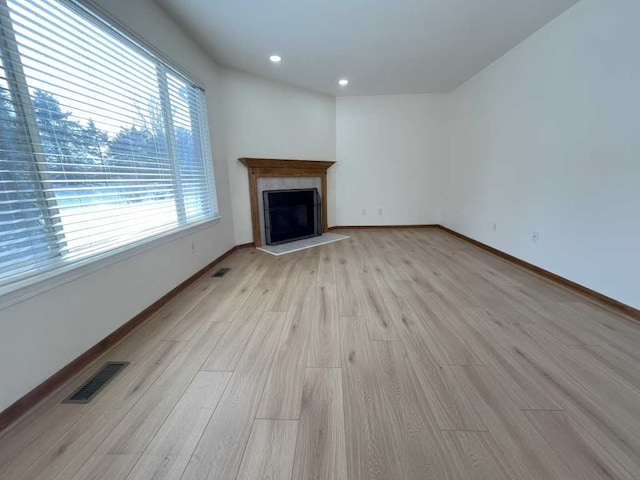 unfurnished living room featuring light wood-style flooring, a fireplace, visible vents, and baseboards