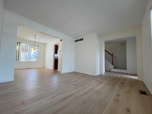 unfurnished living room with light wood-type flooring, stairway, and visible vents