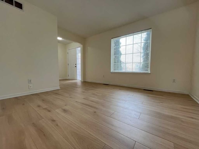 unfurnished room with light wood-type flooring, baseboards, and visible vents