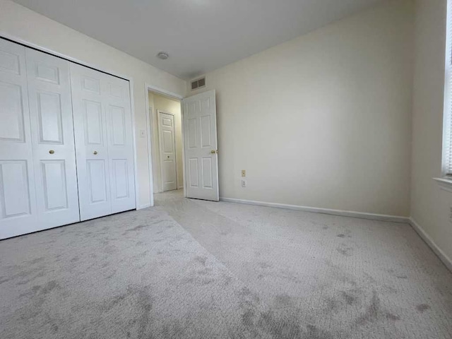 unfurnished bedroom featuring light carpet, baseboards, visible vents, and a closet