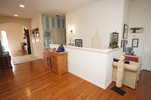 corridor featuring arched walkways, baseboards, recessed lighting, and wood finished floors