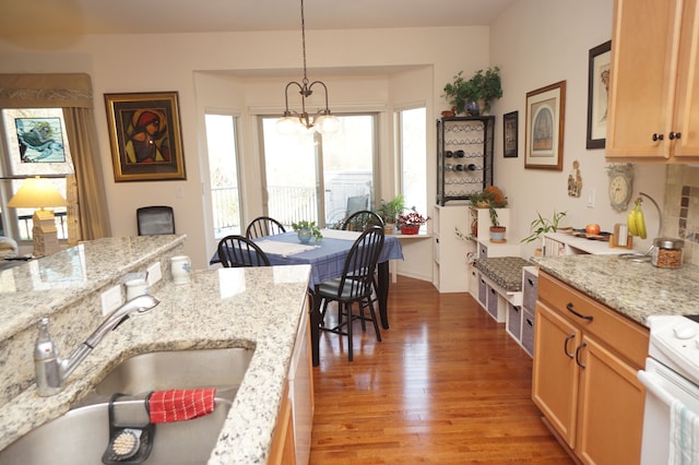 kitchen featuring light stone counters, a sink, light wood finished floors, and decorative light fixtures