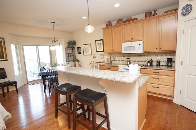 kitchen featuring decorative backsplash, a breakfast bar area, white appliances, and dark wood-type flooring