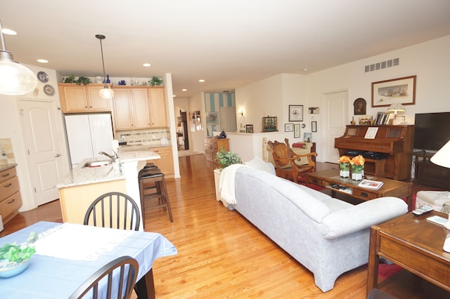 living area with recessed lighting, light wood-style flooring, and visible vents