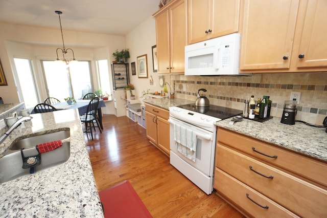 kitchen featuring a sink, light wood finished floors, decorative backsplash, and white appliances