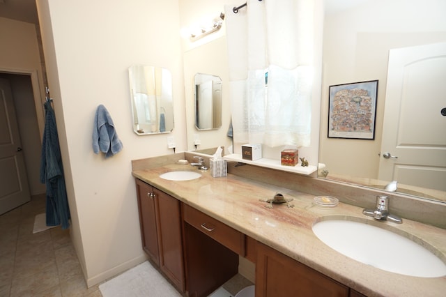 full bathroom featuring double vanity, a sink, baseboards, and tile patterned floors