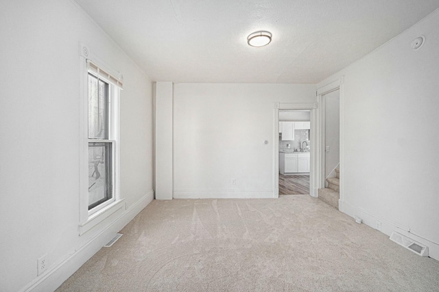 unfurnished room with baseboards, visible vents, stairway, a textured ceiling, and carpet flooring