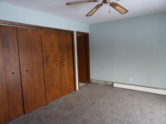 unfurnished bedroom featuring carpet flooring, a ceiling fan, and multiple closets