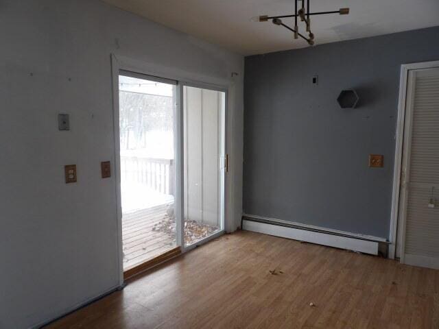 empty room featuring baseboard heating and wood finished floors