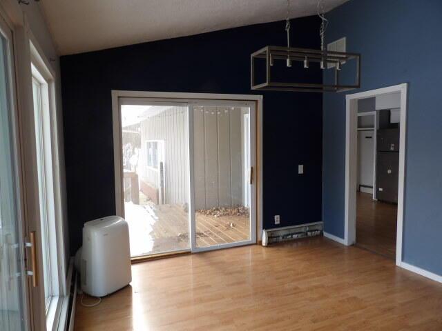 interior space featuring lofted ceiling, baseboards, and wood finished floors