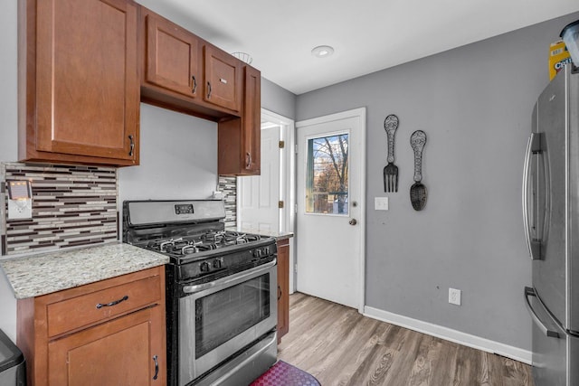 kitchen with tasteful backsplash, brown cabinetry, light wood-style flooring, appliances with stainless steel finishes, and light countertops