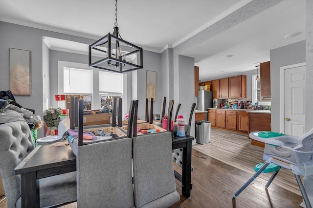 dining space with a healthy amount of sunlight, an inviting chandelier, ornamental molding, and wood finished floors