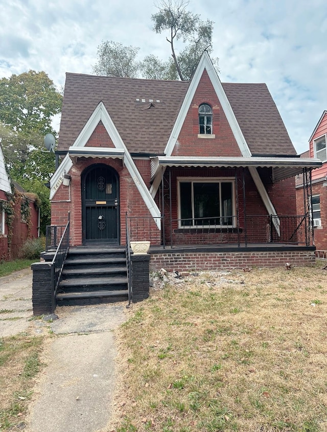 english style home with brick siding and roof with shingles