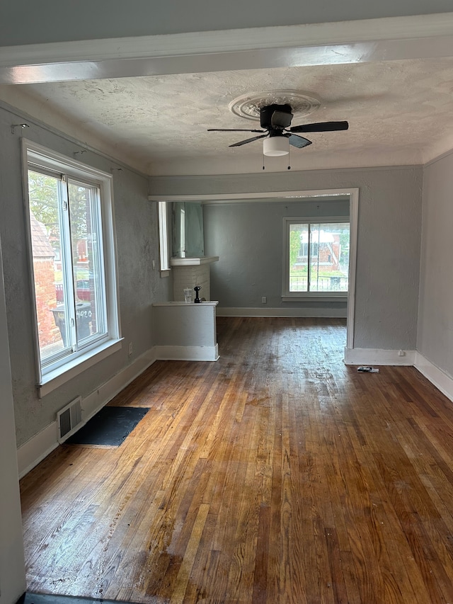 unfurnished living room with visible vents, ceiling fan, baseboards, and wood finished floors